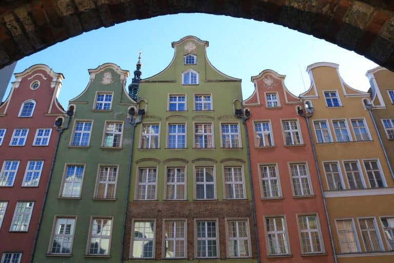 Row of colorful gabled buildings in Gdańsk’s Old Town, featuring green, yellow, and orange facades—showcasing the city’s vibrant architecture and Hanseatic charm.